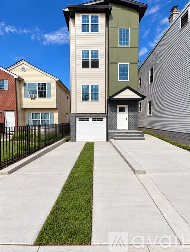 A two-story house with a garage is in front of a grey building.