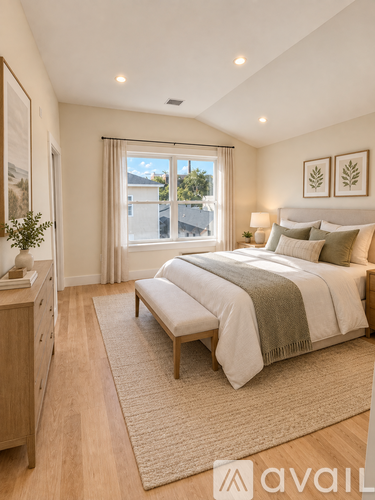 A bedroom with a large bed and a window overlooking a green landscape.