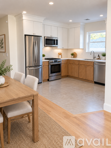 A kitchen with a table and chairs in the foreground and a refrigerator, microwave, oven, and sink in the background.