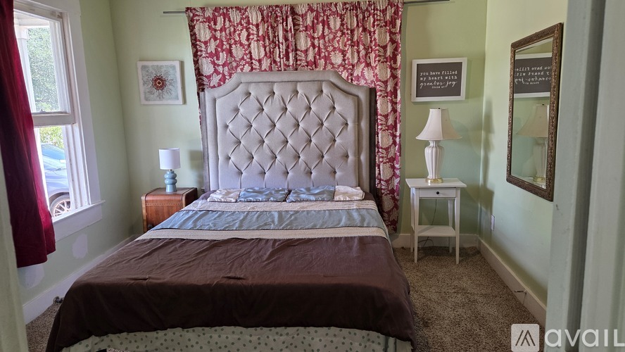 A bedroom with a large bed and a window with red curtains.