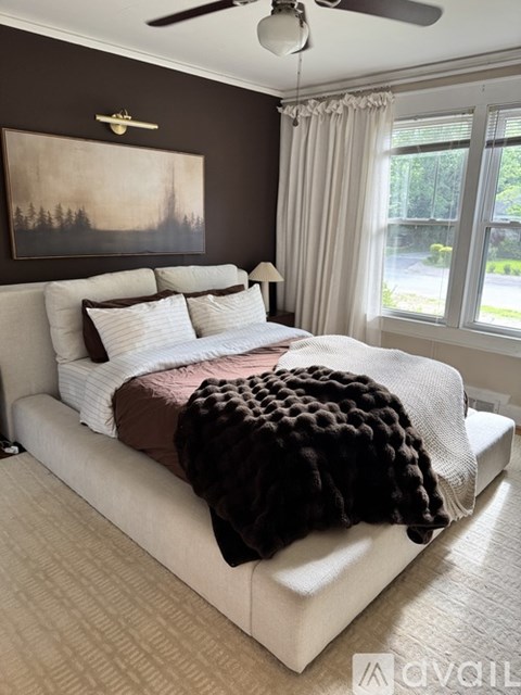 A bedroom with a large bed and a painting on the wall.