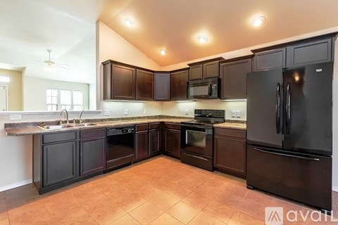 A kitchen with black cabinets and appliances.
