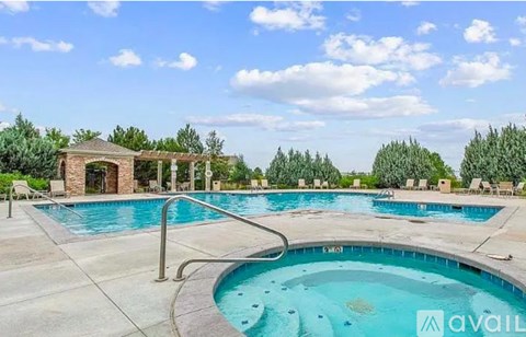 A large outdoor swimming pool with a hot tub and a pavilion.