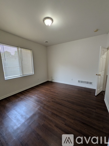 A room with wooden floors and a window with blinds.