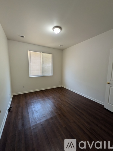 A room with wooden flooring and a window with blinds.