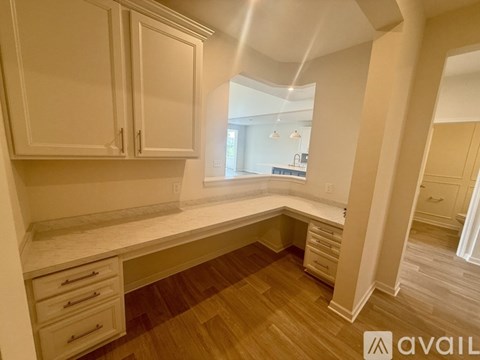A kitchen with white cabinets and a wooden floor.