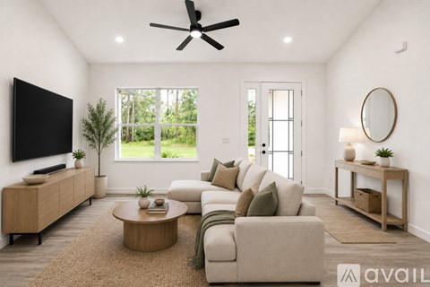 A living room with a large couch, a television, and a ceiling fan.