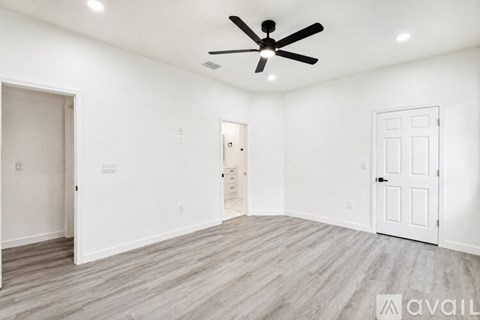 A spacious room with a ceiling fan and lighting fixtures.