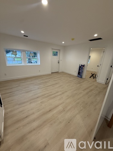 A room with wooden flooring and a window showing a view of a street.