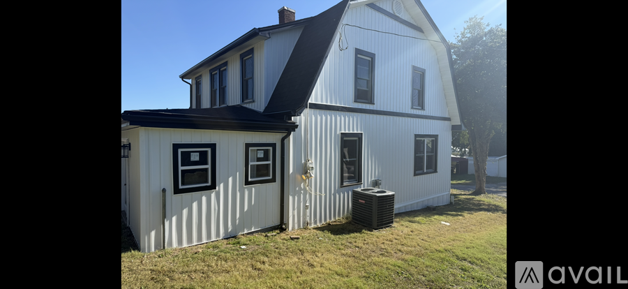 A white house with a black roof and a window with a black frame.