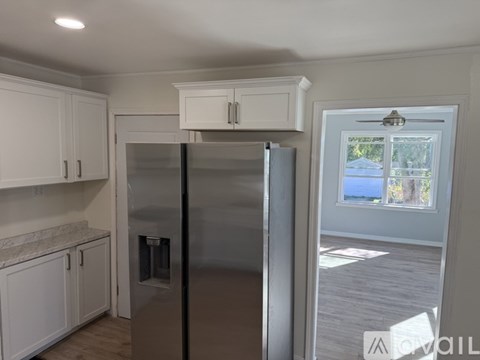 A kitchen with white cabinets and a stainless steel refrigerator.