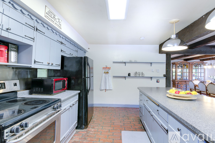 A kitchen with a black refrigerator and stove top oven.