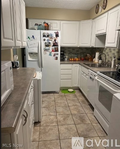 A kitchen with white cabinets and a white refrigerator.
