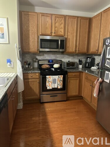 A kitchen with wooden cabinets and a black fridge.