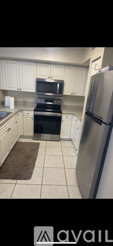 A kitchen with white cabinets and a stainless steel refrigerator.