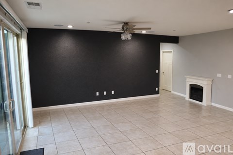A spacious room with a fireplace and a ceiling fan.
