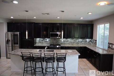 A kitchen with black cabinets and granite countertops.