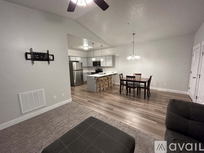 A living room with a grey couch and a kitchen in the background.