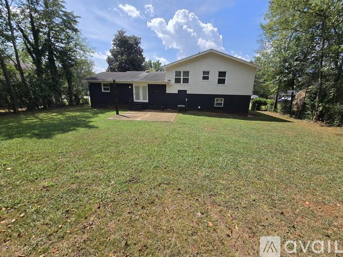 A two-story house with a black and white exterior is surrounded by a grassy yard.
