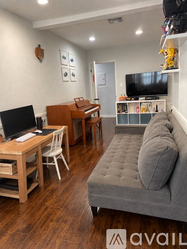 A living room with a grey couch and a wooden desk.