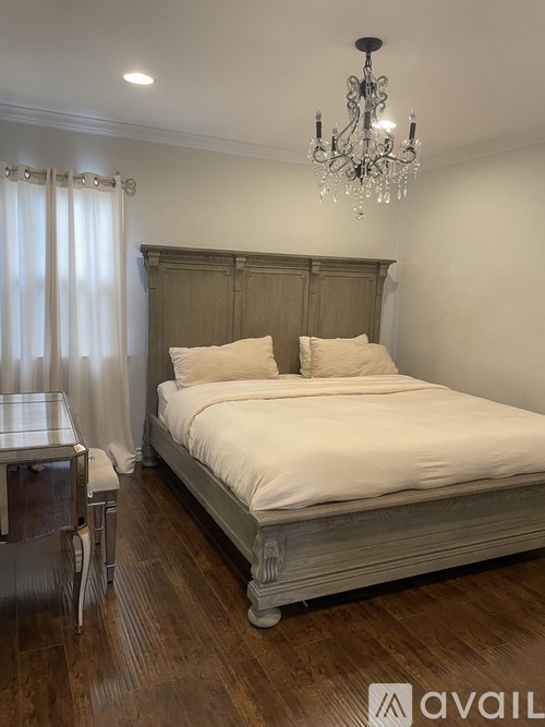 A bedroom with a large bed and a chandelier.