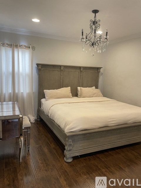 A bedroom with a large bed and a chandelier.