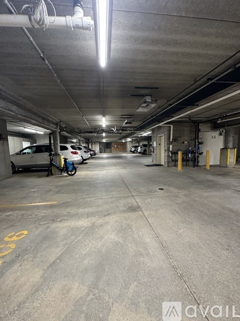 A spacious parking garage with a few cars and a bicycle.