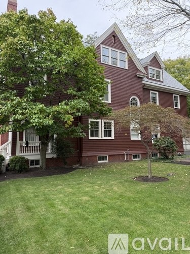 A house with a red brick exterior and a large tree in front.