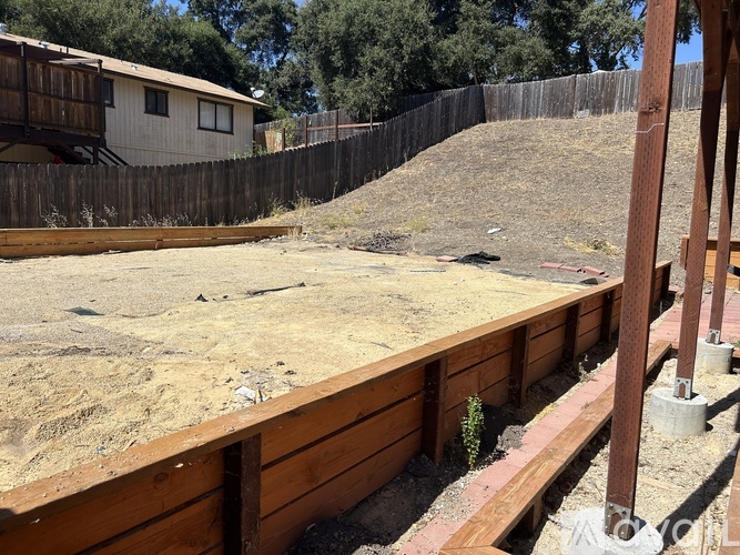 A construction site with a wooden fence and a building in the background.