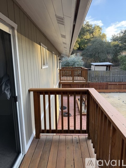 A wooden deck with a railing and a small pool in the backyard.