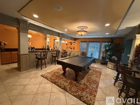 A large room with a pool table and a bar area.