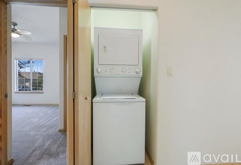 A white dishwasher is in a kitchen with a white wall and a window.