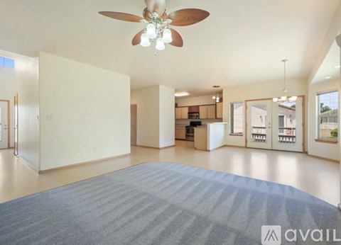 A spacious living room with a ceiling fan and a rug on the floor.