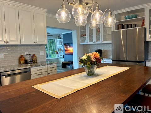 A kitchen with a wooden table and a vase of flowers on it.