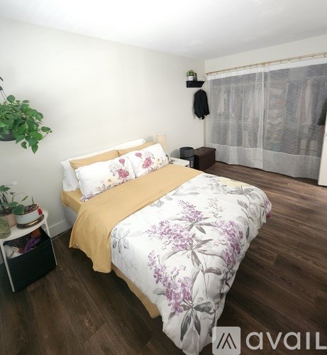 A bedroom with a bed covered in a floral print duvet and a yellow pillowcase.