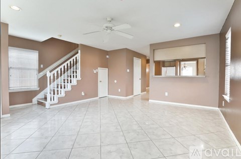 A spacious room with a staircase and a ceiling fan.