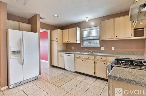A kitchen with a white refrigerator and beige cabinets.