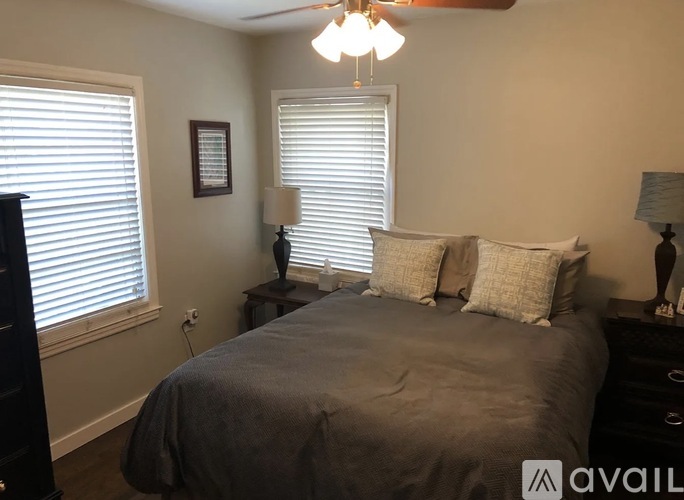 A bedroom with a bed, two lamps, and a picture on the wall.