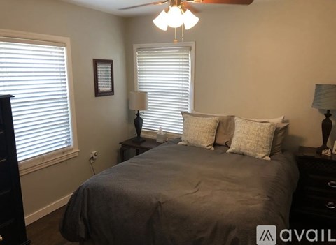 A bedroom with a bed, two lamps, and a picture on the wall.