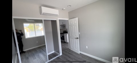A room with a white door and a window with a view of a yellow building outside.