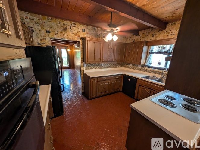 A kitchen with wooden cabinets and a black refrigerator.