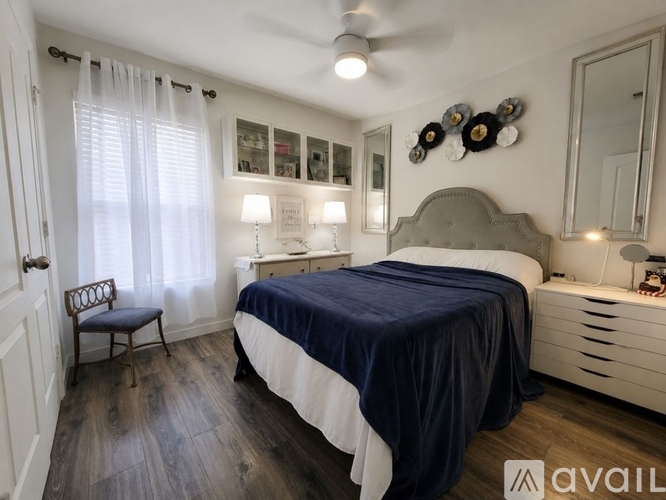 A bedroom with a bed, chair, and a mirror.