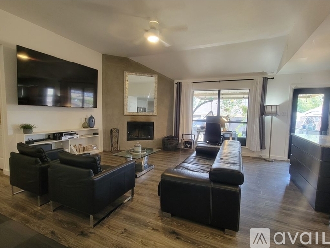 A living room with black leather furniture and a fireplace.