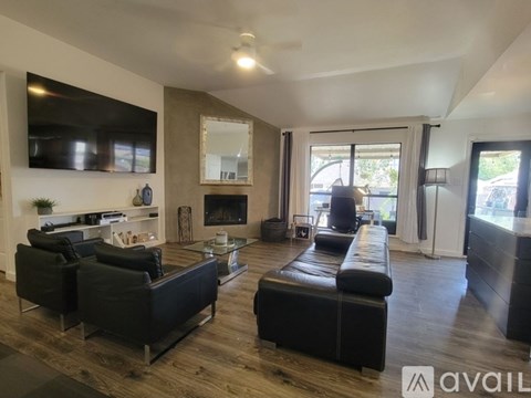 A living room with black leather furniture and a fireplace.