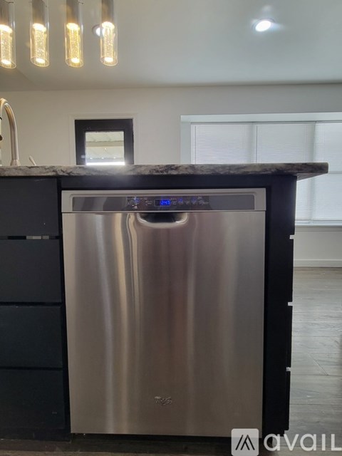 A stainless steel dishwasher is in a kitchen with a black cabinet.