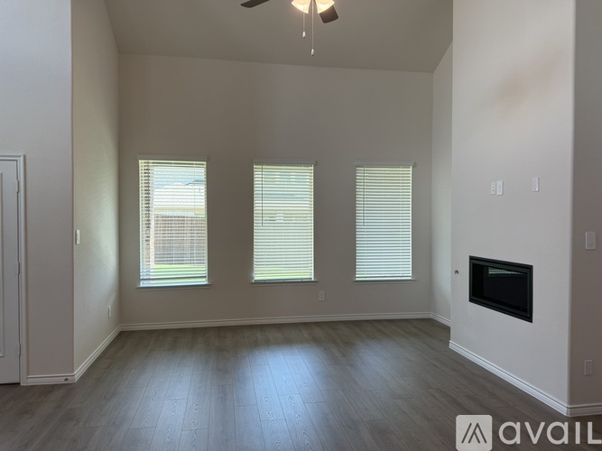 A spacious room with a fireplace and three windows.