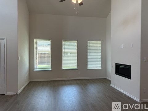 A spacious room with a fireplace and three windows.