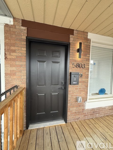 A black door with a number 5803 on the wall above it.