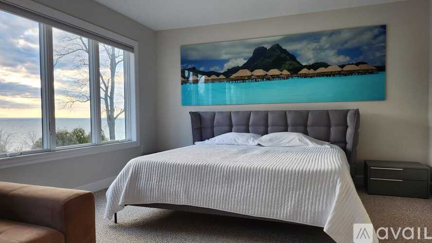 A bedroom with a large bed and a painting of a mountain landscape on the wall.