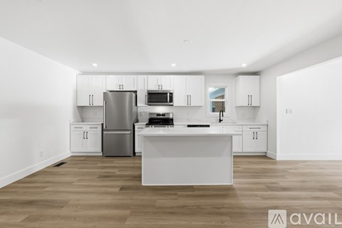A modern kitchen with white cabinets and a wooden floor.